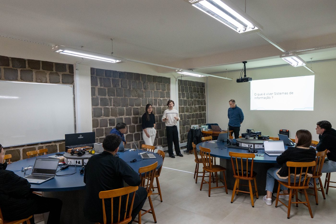 Sala de aula com mesas redondas durante a atividade