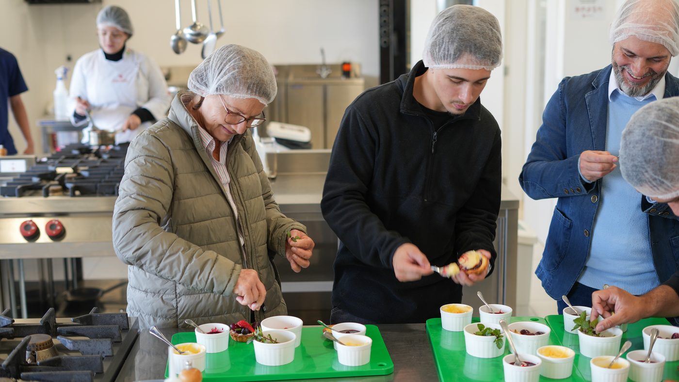 Participantes de touca montando os pratos na cozinha